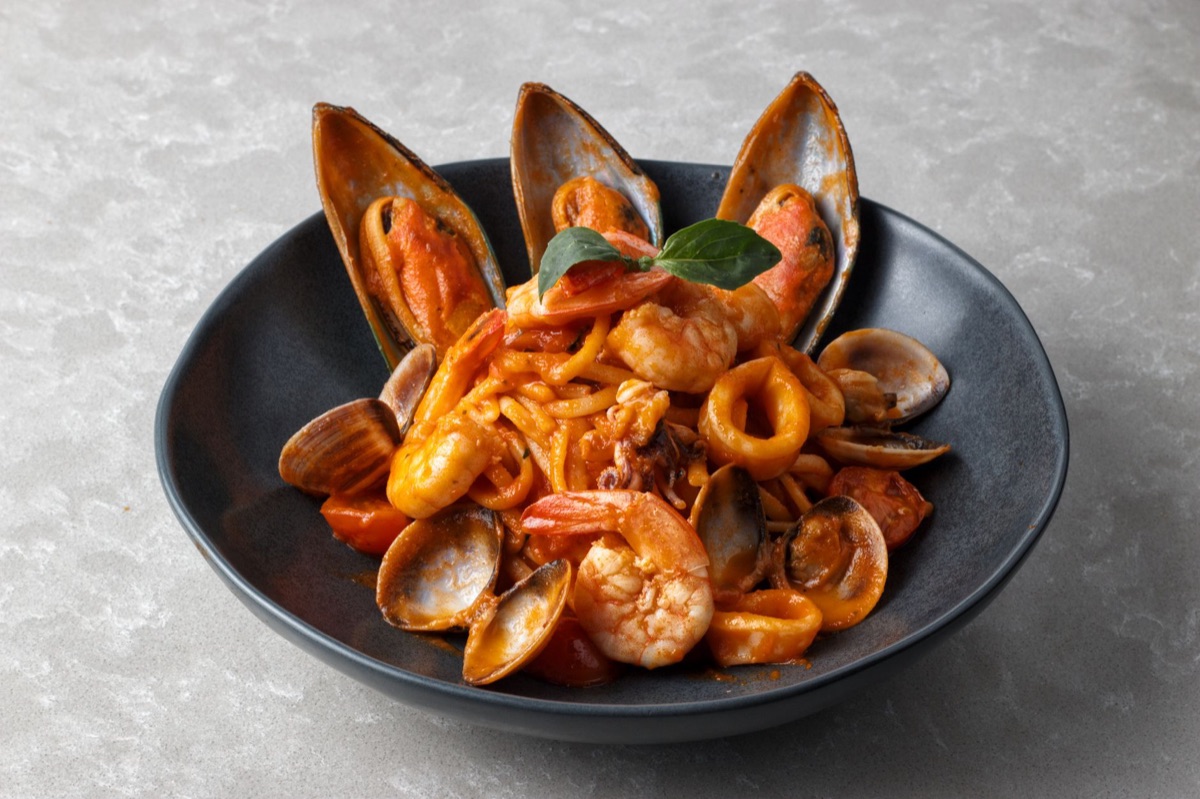 Spaghetti with rich red tomato sauce, fresh basil leaves, and seafood.