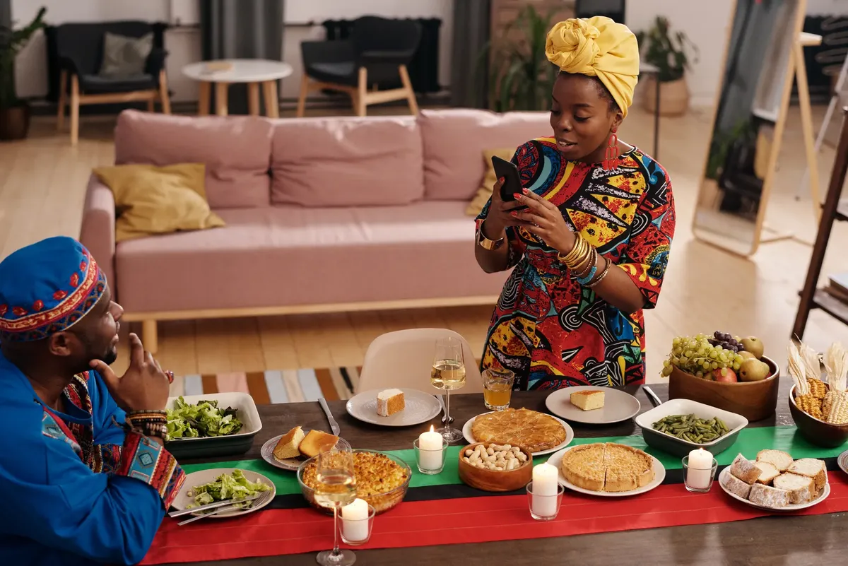 A joyful family celebrating Kwanzaa with traditional food and colorful attire indoors.