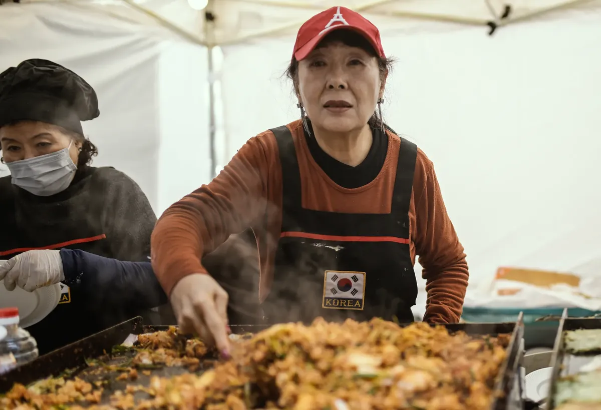 A Korean vendor cooking traditional street food at a Buenos Aires market stall.