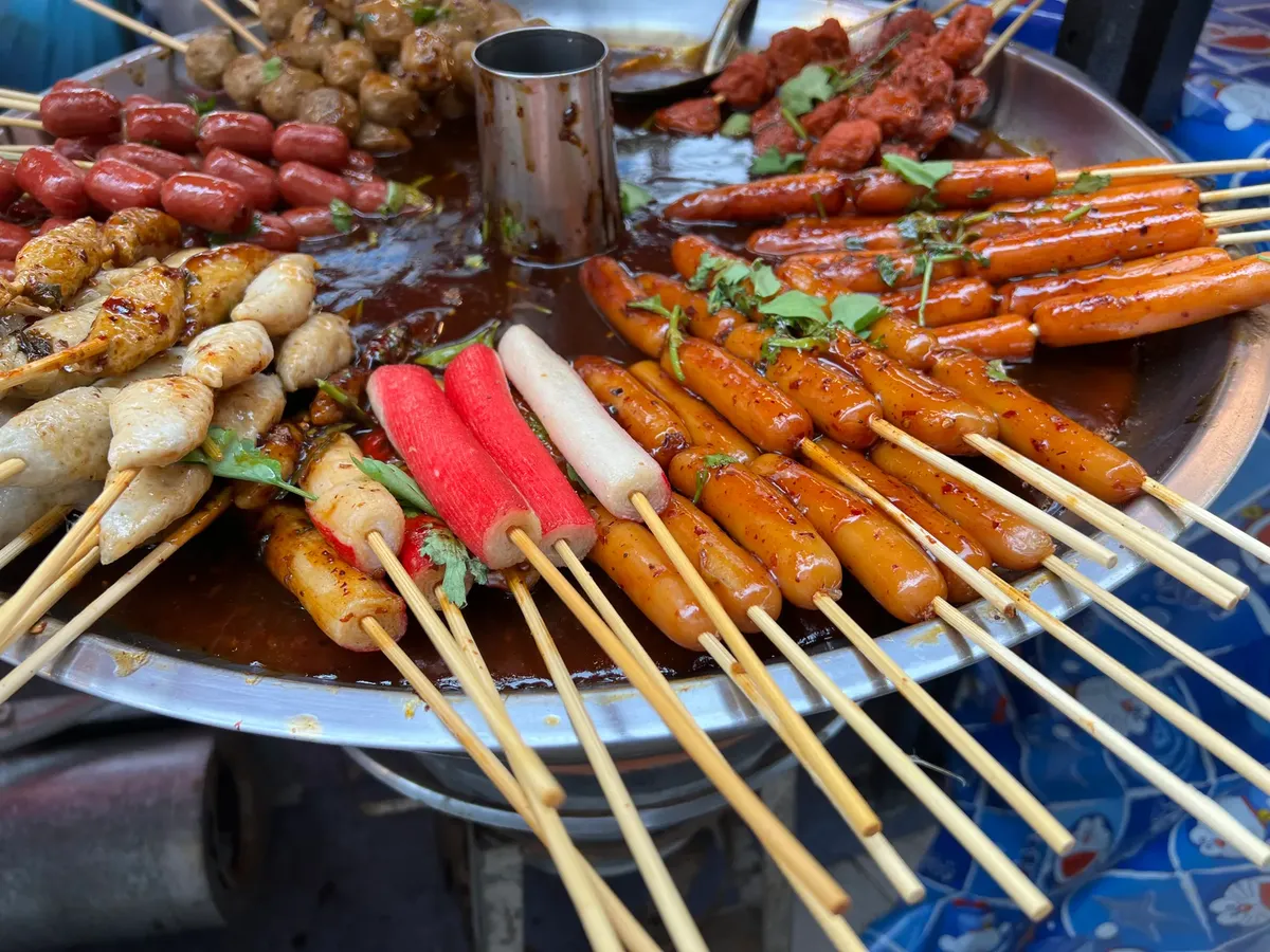 A vibrant display of various skewered street foods in sauce, perfect for Asian food enthusiasts.