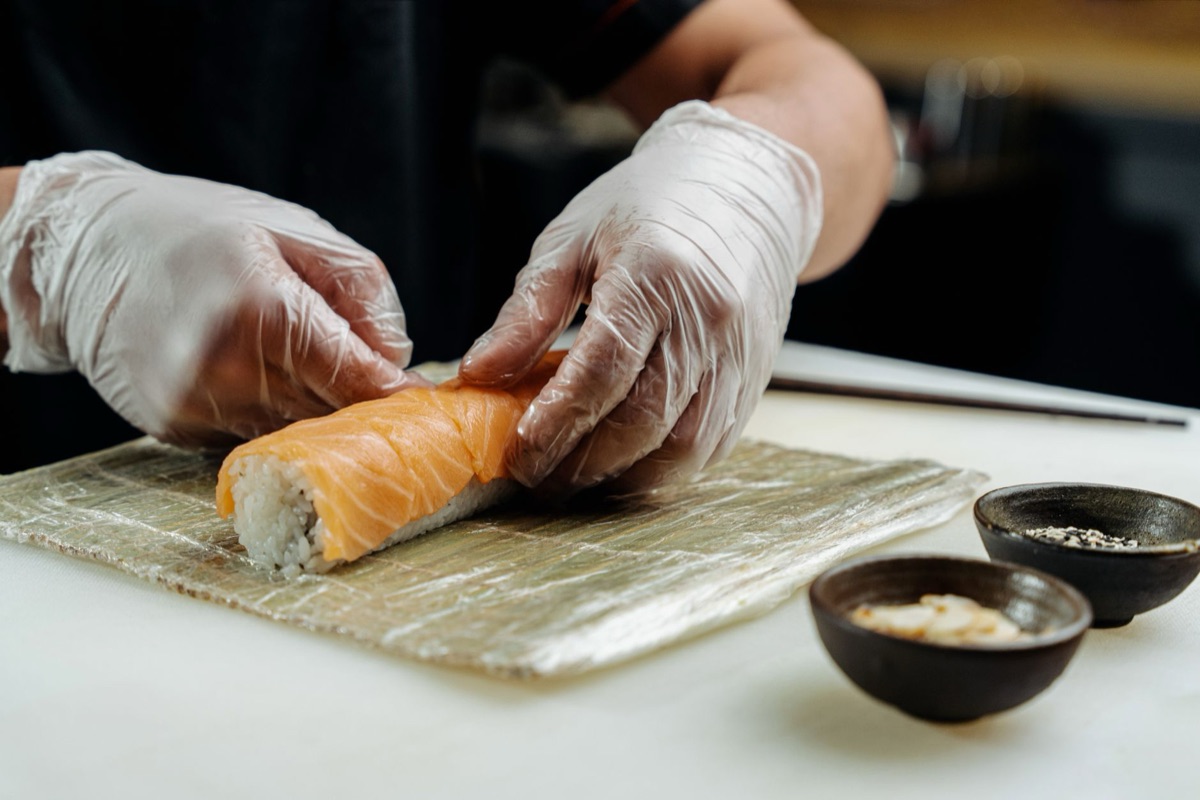 De handen van een sushi-meester die rijst vormen