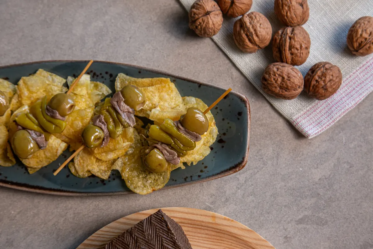 Delicious Spanish tapas featuring olives, anchovies, and walnuts on a rustic plate.